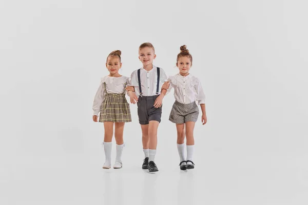 Portret Trojga Dzieci Stylowych Ubraniach Spacerujących Razem Szarym Tle Pracowni — Zdjęcie stockowe