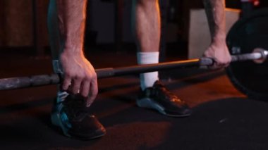 Yakından sporcular halterle el ele tutuşuyor. Spor salonunda halterli ve neon ışıklı filtreli spor giyim eğitiminde genç güçlü kaslı bir adam. Ağırlık kaldırma egzersizi. Enerji, güç, spor kavramı
