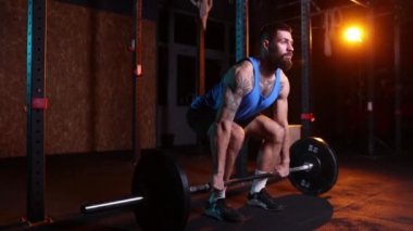Sporcu barı kaldırır. Spor salonunda halterli ve neon ışıklı filtreli spor giyim eğitiminde genç güçlü kaslı bir adam. Ağırlık kaldırma egzersizi. Enerji, güç, spor ve sağlıklı yaşam tarzı kavramı