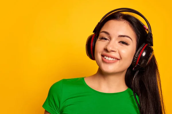 stock image Lovely sounds. Closeup young girl, student with long flowing hair in headphones dancing isolated on yellow color background. Concept of beauty, art, fashion, youth, lifestyle, music, party. Copy space