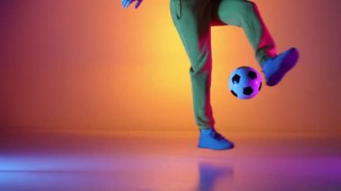 Kafkasyalı profesyonel futbolcu futbol topuyla bacaklarında hokkabazlık yapıyor, neon ışığı var. Profesyonel futbolcunun stüdyo çekimi, modern şehir gençlik kıyafetleri giyen adam. Spor, serbest stil