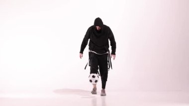 Genç erkek oyuncu yerdeki beyaz stüdyoda futbol topuyla hokkabazlık yapıyor. Kafkasyalı profesyonel futbolcu. Modern şehir gençlik kıyafetleri giymiş bir erkek ya da erkek. Spor, spor, serbest stil konsepti