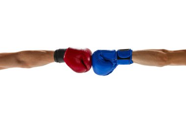 Kırmızı ve mavi boks eldivenli iki erkek el, beyaz arka planda izole bir şekilde birbirine çarpıyor. İlan için boşluk kopyala, metin yaz. Spor, rekabet, mücadele ve dövüş sporları