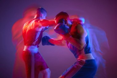 Yumruk at. Mor arka planda neon ışıkta izole edilmiş iki profesyonel boksör portresi. Spor anlayışı, rekabet, eğitim, enerji. İlan, metin için boşluk kopyala