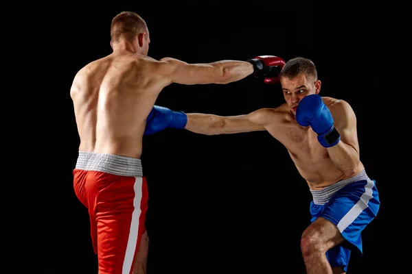 濃い背景に隔離された青と赤のスポーツユニフォーム練習パンチの男性プロボクサー スポーツ トレーニング エネルギーの概念 2人の双子の兄弟が動き — ストック写真