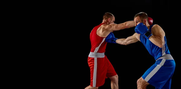 濃い背景に隔離された青と赤のスポーツユニフォーム練習パンチの男性プロボクサー スポーツ トレーニング エネルギーの概念 2人の双子の兄弟が動き — ストック写真