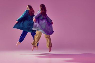 Ağırlıksızlık, hareket kolaylığı. Genç, şık, modaya uygun dans eden kadın. Pembe arka planda izole edilmiş bir şekilde. Modern sanat, moda, gençlik tarzı ve yaratıcılık kavramı