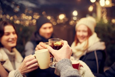 Dostça bir parti. Emotif gülümseyen erkekler ve kadınlar ellerinde kupalar dolusu sıcak şarapla eğleniyorlar, kış fuarında birlikte vakit geçiriyorlar. Keyif alıyorlar, sıcak giyiniyorlar.