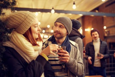 Noel tatili ve partilerde yeni tanıdıklar. Sıcak içeceklerle romantik bir randevuda mutlu bir adam ve kız. Duygular, tatiller, aşk, arkadaşlık kavramı. Neşeli ve mutlu görün.