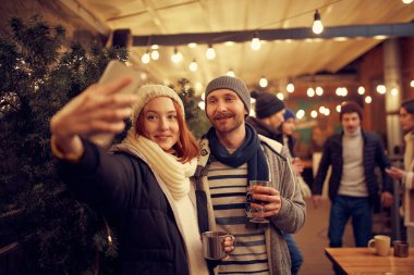 Noel tatili ve partilerde yeni tanıdıklar. Sıcak içeceklerle romantik bir randevuda mutlu bir adam ve kız. Duygular, tatiller, aşk, arkadaşlık kavramı. Neşeli ve mutlu görün.