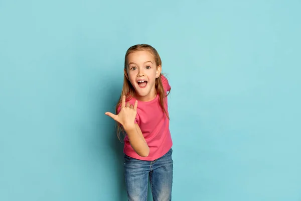 一个漂亮的小女孩的画像 穿着粉色T恤衫的孩子 在蓝色的工作室背景下有着快乐的情绪 童年的概念 面部表情 生活方式 活跃的孩子 — 图库照片