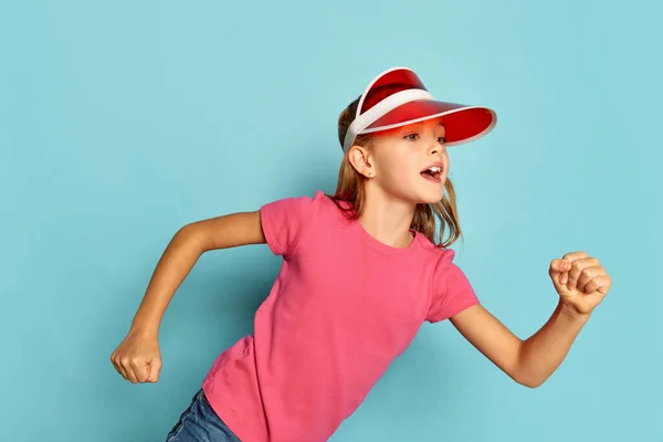 一个漂亮的小女孩的画像 穿着粉色T恤的孩子头戴塑料帽 与蓝色的工作室背景隔离 多愁善感的孩子童年 面部表情 生活方式的概念 — 图库照片