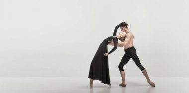 Genç adam ve kadın, bale dansçıları gri stüdyo arka planında izole bir şekilde gösteri yapıyorlar. Tutkulu bir ilişki. Klasik dans estetiği, koreografi, sanat, güzellik kavramı. İlan için alanı kopyala