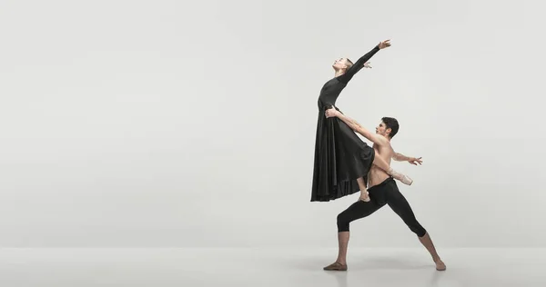 Young man and woman, ballet dancers performing isolated over grey studio background. Support and fly. FLyer. Concept of classical dance aesthetics, choreography, art, beauty. Copy space for ad