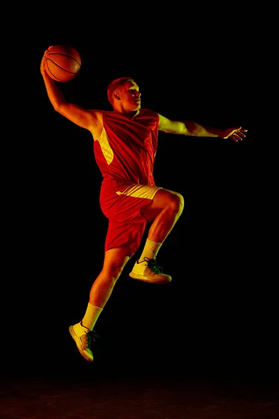 年轻活跃运动员的动态肖像 身穿运动服的男篮选手穿着球衣练习 在霓虹灯下在黑暗的背景下飘逸 广告的复制空间 — 图库照片