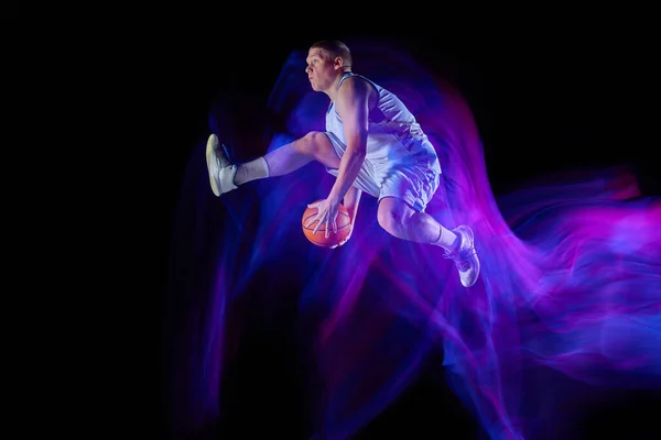 大きなエネルギーだ 若いアクティブなアスリートのスタジオショット 運動中のスポーツのユニフォームを着た男性バスケットボール選手と混合ネオンの光の暗い背景の上に孤立ボールと行動 広告のコピースペース — ストック写真