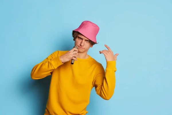 一个有着卷曲头发的年轻人的画像 穿着粉红色的全景 在蓝色的背景下唱着孤独寂寞的歌 著名的表演者 青春文化 面部表情 时尚的概念 广告的复制空间 — 图库照片