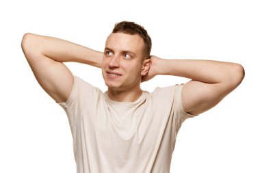 Beyaz stüdyo arka planında izole edilmiş günlük tişörtle poz veren genç bir adamın portresi. Sağlıklılık. Sportif yaşam tarzı. Erkek sağlığı, kendine bakım, vücut ve cilt bakımı kavramı. İlan için alanı kopyala