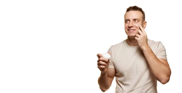 白いスタジオの背景に隔離されたシェービングの後にクリームを適用する明確な滑らかな顔を持つ若い男の肖像画 保湿効果あり 男性の健康 セルフケア ボディケア スキンケアの概念 広告のコピースペース — ストック写真