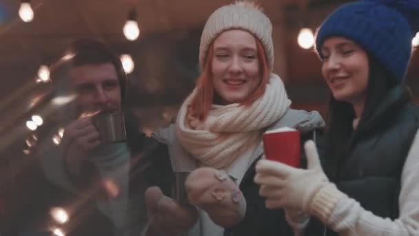 圣诞气氛 年轻快乐的男男女女穿着保暖的衣服 在冬日的传统集市上共度时光 喝着热饮 自得其乐 穿着温暖 面面相觑 开怀大笑 — 图库视频影像