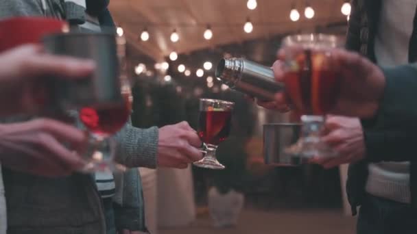 ホット モールド ワインのホット カップ マグカップを手にしたクローズアップ マンと女性 幸せな休日 国家の伝統 冬のストリートフェア クリスマスのコンセプト — ストック動画