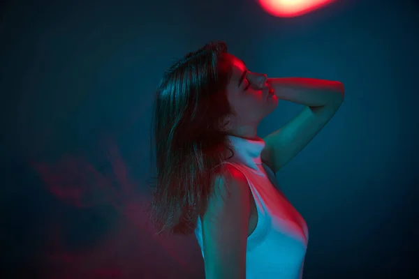 生活方式 年轻美丽女子的画像 在蓝色工作室背景上 在红色霓虹灯下独立跳舞 青春文化 面部表情 时尚的概念 广告的复制空间 — 图库照片