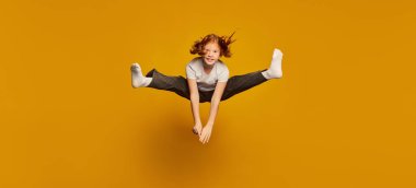 Eğlenmene bak. Mutlu küçük kız, beyaz tişörtlü çocuk ve kot pantolon sarı arka planda yüksek izole atlama. Çocuklar moda, duygular, tasasız çocukluk, zorluklar, eğitim kavramı