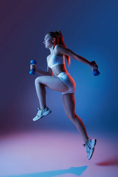Beyaz Spor Giyim Eğitimli Genç Bir Kız Dambılları Neon Işıkta — Stok fotoğraf