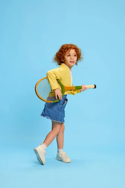 可爱的小女孩的画像 一头卷曲的红头发 与羽毛球球拍隔离在蓝色的背景下 童年的概念 生活方式 广告的复制空间 — 图库照片