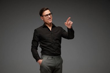 Siyah iş adamı, klasik tişört ve gri arka planda izole edilmiş gri pantolon giymiş gülümseyen genç adam. İş adamının modaya uygun görünüşü. İş anlayışı, gençlik, modern yaşam tarzı.