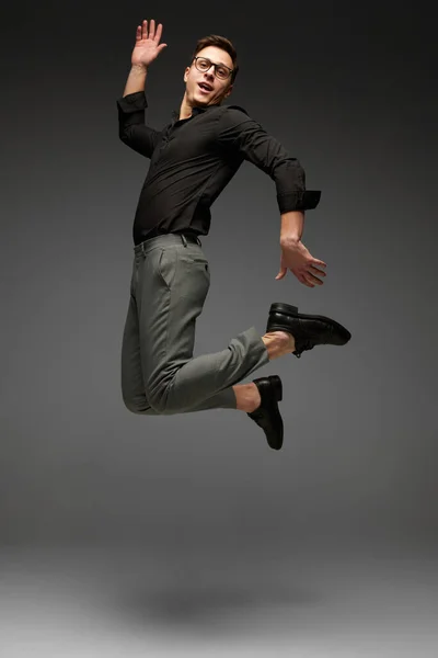 ハイジャンプだ 幸せな若い男 黒の古典的なスタイルのシャツとグレーのズボンを実行してビジネス 灰色の背景に孤立ジャンプします モダンなオフィススタイル アクティブなライフスタイル — ストック写真