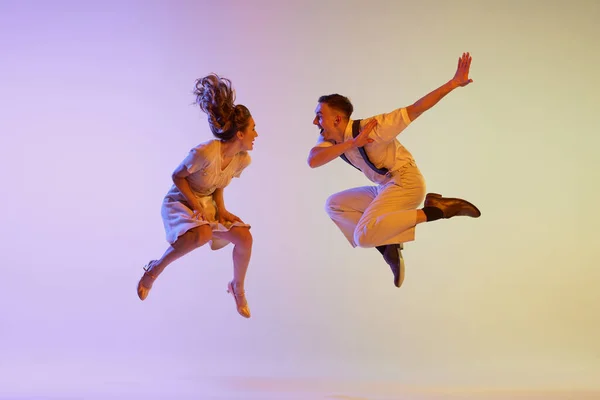 音乐表演 穿着复古风格服装的感情用事的一对舞伴 在霓虹灯下 在渐变的紫丁香背景下独立地跳着社交舞 动作和动作中的舞者 — 图库照片