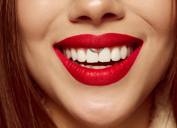 Closeup view of female mouth with bright red lipstick. Beautiful wide smile of young woman with great healthy white teeth and well kept skin. Health, beauty, wellness, art and ad concept