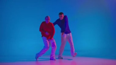 Müziği. Şık erkek ve kadın parlak spor kıyafetlerle neon ışıkta dans pistinde dans ediyorlar. Modern gençlik kültürü, hareketler, tarz ve moda kavramı, eylem.