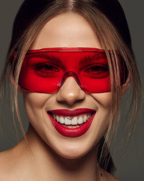 漂亮的年轻女子戴着时髦的红色眼镜 在深灰色背景下微笑的特写 牙齿护理 情绪及广告 — 图库照片