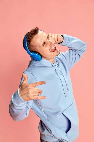 Portret Młodego Mężczyzny Kapturze Słuchającego Muzyki Słuchawkach Śpiewającego Różowym Tle — Zdjęcie stockowe