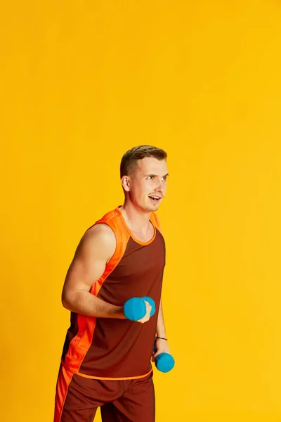身穿橙色制服 体重减轻 双手肌肉发达的年轻人的画像 在黄色背景上显得孤立无援 运动的概念 健身生活方式 身体护理 — 图库照片