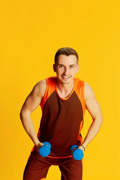 オレンジの制服の訓練で若い男の肖像画 黄色の背景に隔離されたスポーツ用品とポーズ スポーツ フィットネスライフスタイル ボディケア アクションの概念 — ストック写真