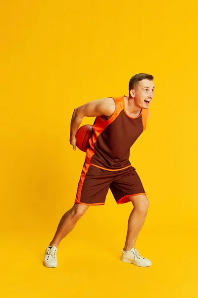 Portret Młodego Człowieka Pomarańczowym Mundurze Grającego Koszykówkę Żółtym Tle Pojęcie — Zdjęcie stockowe