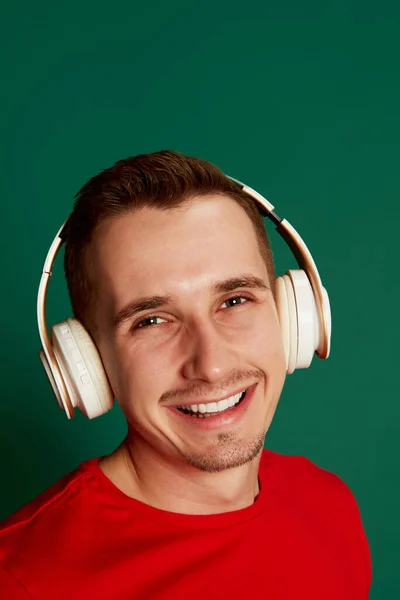 Portrét Mladého Usmívajícího Muže Červeném Tričku Pózujícího Sluchátkách Izolovaných Zeleném — Stock fotografie