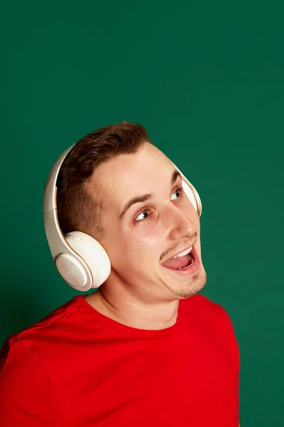 Portret Młodego Uśmiechniętego Mężczyzny Czerwonej Koszulce Pozującego Słuchawkach Odizolowanych Zielonym — Zdjęcie stockowe
