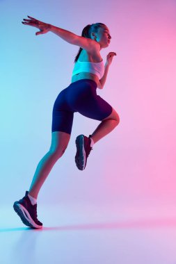 Genç sportif kadın eğitiminin alt görüntüsü, neon ışıklarıyla izole edilmiş mavi arka planda koşuyor. Spor, güç, vücut bakımı, fitness, refah, sağlık kavramı. Ad