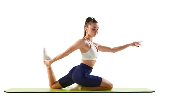年轻女运动员训练的肖像 在白色背景上隔离的运动垫上做伸展运动 运动的概念 身体护理 — 图库照片