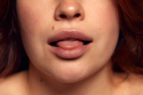 Close-up view of female perfect shape mouth with nude colored lipstick. Moisturizing care. Cosmetological lip fillers. Concept of natural beauty, cosmetics, emotions, lips augmentation