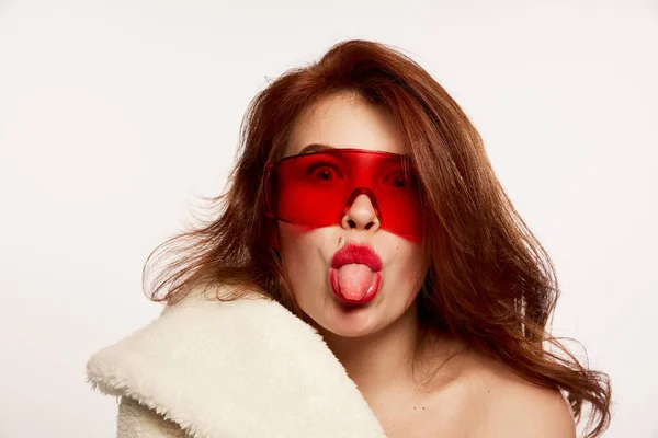 毛皮のコートを着た若い美しい赤い髪の女性と白い背景に隔離された赤いトレンディーなメガネの肖像画 感情的よ ハイトファッション スタイル メイクアップ 美しさ 雑誌スタイル 広告の概念 — ストック写真
