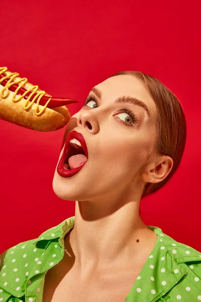年轻女人的情绪吃辣热狗芥末和辣椒过鲜红的背景 胡椒而不是香肠 食品流行艺术摄影 互补的颜色 文字的复制空间 — 图库照片