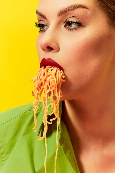 照片中年轻女孩吃意大利面 面条在黄色背景下从嘴里伸出来 复古风格 食品流行艺术摄影 互补的颜色 文字的复制空间 — 图库照片