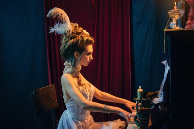 Klasik müziğin performansı. Ortaçağ 'da yaşayan, zarif beyaz elbiseli ve çalan genç ve güzel bir kadın. Dönem, güzellik, tarih, sanat, yaratıcılık karşılaştırması.