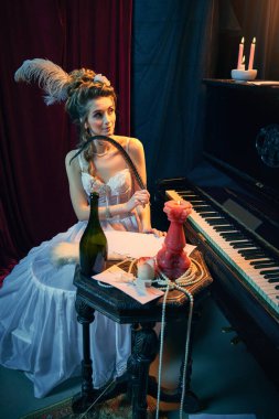Ortaçağ beyaz elbisesi içinde piyanonun başında oturmuş roman yazan güzel bir kızın portresi. Dönem, güzellik, tarih, sanat, yaratıcılık karşılaştırması.