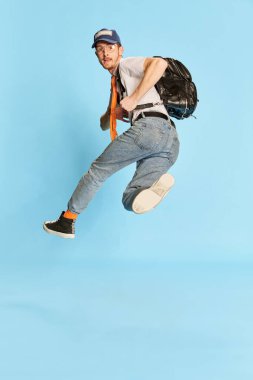 Genç bir adamın portresi, günlük giysiler içinde mavi arka planda izole edilmiş bir şekilde poz veren bir öğrenci. Tatil zamanı. Gençlik kavramı, yaşam tarzı, eğitim, duygular, yüz ifadesi. Ad